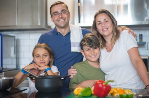 A joyful family of four cooking together in a modern kitchen, highlighting family bonding and culinary activities.