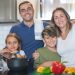 A joyful family of four cooking together in a modern kitchen, highlighting family bonding and culinary activities.