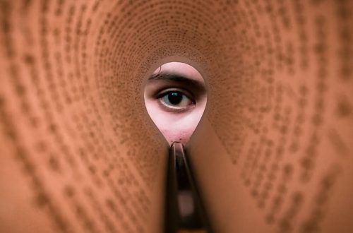 A person's eye looking through a rolled book page, creating a unique viewpoint.